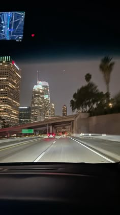 the view from inside a car driving down a highway with tall buildings in the background