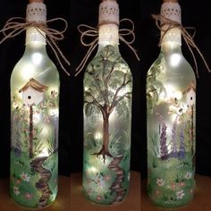 three glass bottles decorated with trees and lights