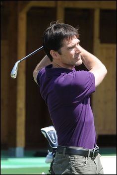 a man in purple shirt swinging a golf club