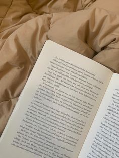 an open book sitting on top of a bed