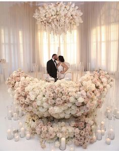 a bride and groom kissing in front of a large arrangement of flowers