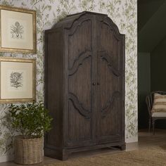 an armoire in the corner of a room with wallpaper and pictures on the walls