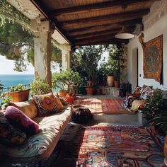 a covered porch with lots of pillows and rugs on the floor next to an ocean view