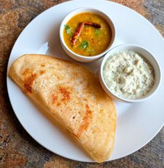 a white plate topped with two quesadillas next to bowls of dip