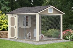 two dogs in a dog kennel outside on the grass with flowers and trees behind them