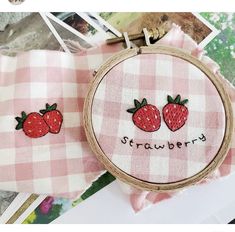 two embroidered strawberries on pink and white checkered fabric, with the words strawberry