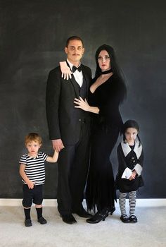 a man, woman and two children standing in front of a chalkboard wall with black writing on it