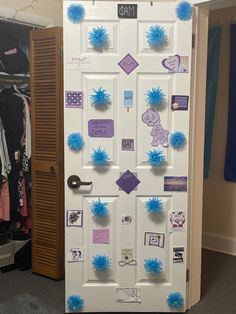 a white door decorated with blue pom - poms and purple letters on it