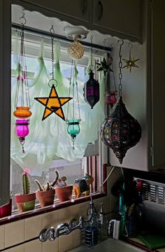 a kitchen sink under a window filled with pots and pans hanging from the ceiling