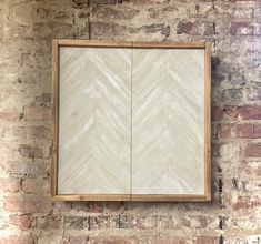 a wooden frame hanging on the side of a brick wall next to a mirror with an arrow pattern