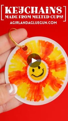 a hand holding a yellow and red tie dye smiley face ornament on a red background with the words ketchins made from melted cups