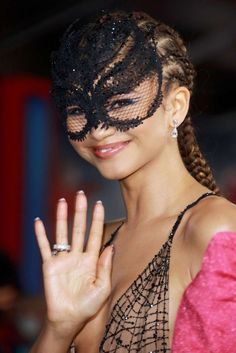 a woman wearing a black mask and holding her hand up