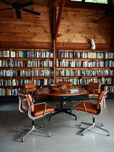 an office with two chairs and a table in front of a book shelf filled with books