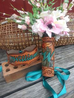 two vases that have flowers in them on a wooden table next to a basket