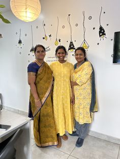 two women standing next to each other in front of a wall with hanging decorations on it