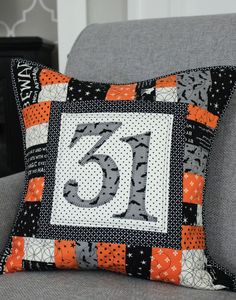 a gray couch with a black and orange pillow on it