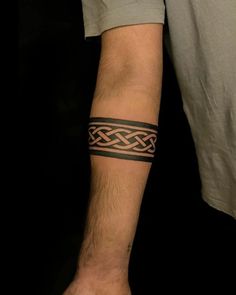 a man with a tattoo on his arm holding onto another person's hand and wearing a wrist band