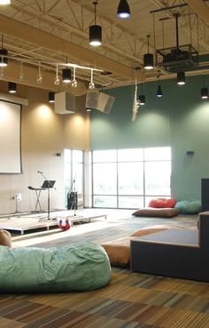 an empty room with couches, chairs and projector screens on the wall behind them