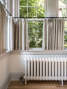 a radiator in front of a window with curtains