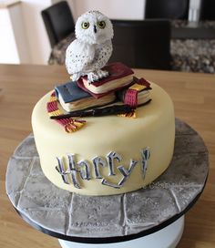 a cake decorated with an owl sitting on top of a stack of books and the words harry written on it