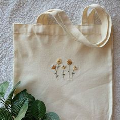 a tote bag with three flowers embroidered on it