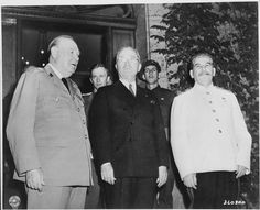 an old black and white photo of men in suits standing next to each other with one man looking at the camera