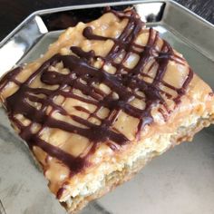 a piece of cake with chocolate drizzled on it sitting in a metal pan