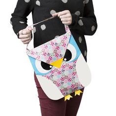 a woman holding an owl shaped kite in her right hand and wearing a black shirt with polka dots on it