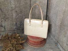 1950s cream handbag by Holzman Originals Body of bag 8.5" width 21.5cm 6.5" height 16.5cm Height with handles  11.5" 29.2cm Very pretty delicate little handbag from the 1950s. Double handles with two small bows to the front. Gold clasp in good working order. Two souffle sides and finely piped around each side. It has two interior pockets and a clasped inner purse with a further 3 pockets and a zipped pocket too. The inside is very clean and made in warm yellow satin and it has a matching coin pu Cream Handbag, Beige Handbag, Cream Bag, Black Wrapping Paper, Beige Handbags, Cream Bags, Yellow Satin, Top Handle Bags, Small Bows