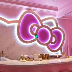 a counter with some drinks on it in front of a hello kitty sign and pink walls