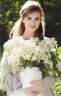 a woman holding a vase full of white flowers