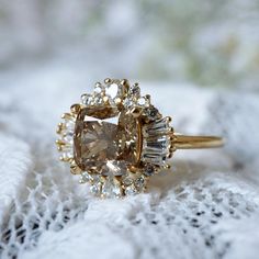 an engagement ring with a fancy yellow diamond surrounded by small white and clear stones on a lace surface