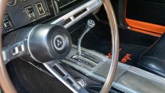 the interior of an old car with black leather and orange trims, including steering wheel