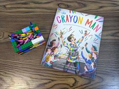 the crayon man book next to colored crayons on a wooden table