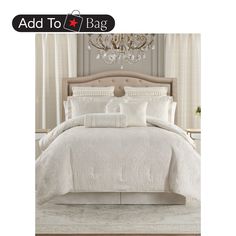 a bed with white comforter and pillows on top of it in front of a chandelier