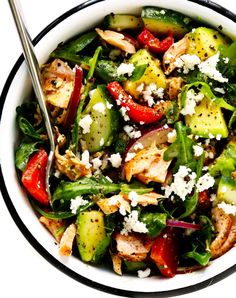 a white bowl filled with vegetables and topped with feta cheese