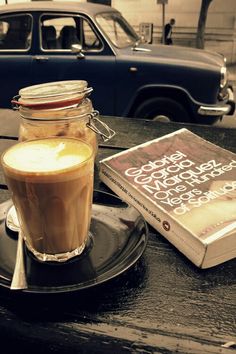 a cup of coffee sitting on top of a table next to a book and a car