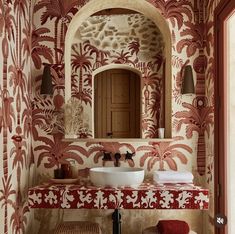 a bathroom with red and white wallpaper on the walls, two sinks and a mirror