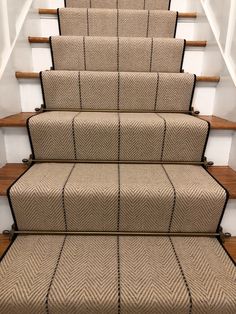 a set of stairs with beige carpet and wooden handrails