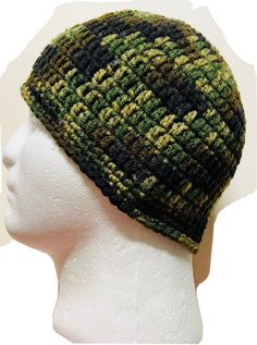 a white mannequin head wearing a green and black knitted beanie hat