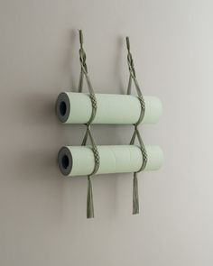 three rolls of toilet paper hanging on a wall with some cords attached to the sides