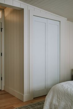 an empty bedroom with white walls and wood flooring is pictured in this image, the closet doors are open