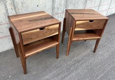 two wooden nightstands sitting next to each other on the ground in front of a concrete wall