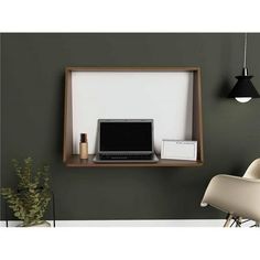 a laptop computer sitting on top of a wooden shelf next to a white chair and potted plant