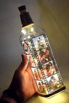 someone is holding up a bottle that has pictures on it and lights in the shape of film strips