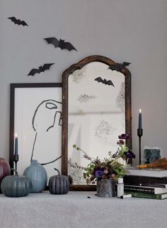 a mantle with candles, vases and bats on it in front of a mirror