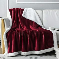 a couch covered in a red and white blanket next to a coffee cup on a table