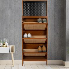 a wooden shelf with baskets and candles on it next to a white table in front of a gray wall