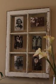 a vase with flowers in it sitting next to an old window pane filled with photos