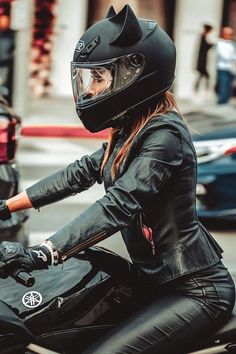 a woman in black leather riding on the back of a motorcycle